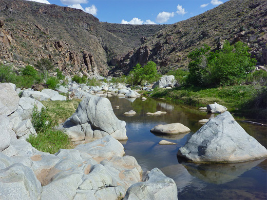 Calm water of the Agua Fria River, lined by smooth boulders