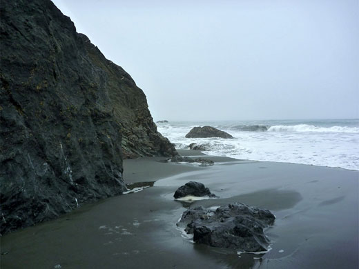 White surf and dark grey sand