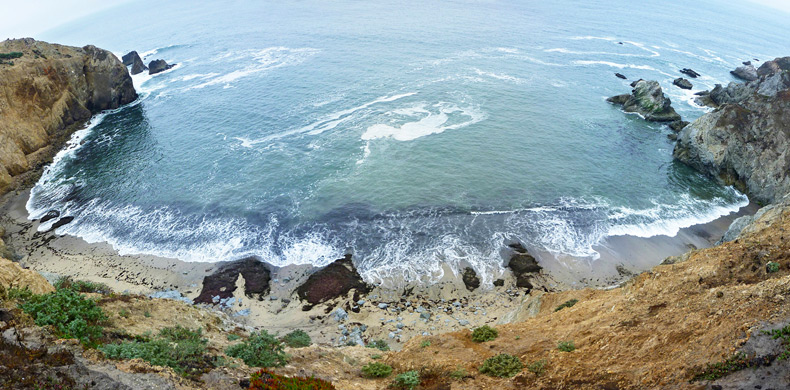 Sandy beach, lined by near-vertical cliffs