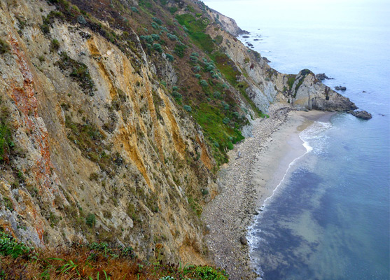 Steep, colorful cliffs above a narrow beach