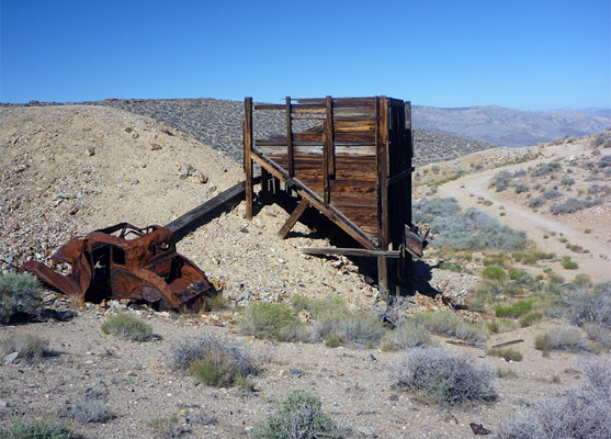 Rusty car and wooden hopper, at Skidoo