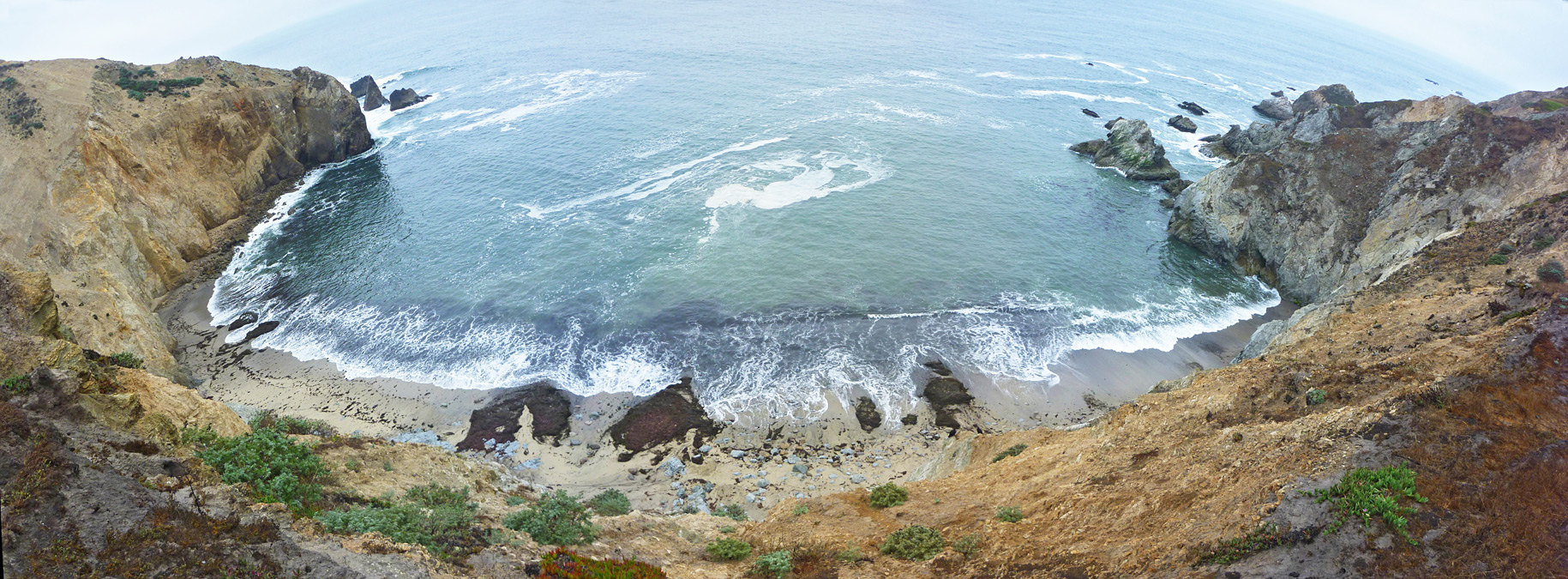 Sandy beach, lined by near-vertical cliffs