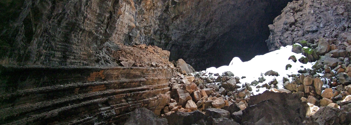 Boulders and a patch of snow, beneath one of the entrances to Big Skylight Cave