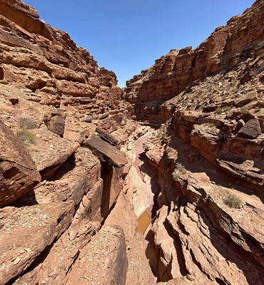 Muddy pool below a narrow dryfall